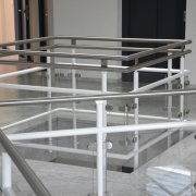 Geländer aus weiß lackiertem Stahl mit Glasscheiben in einem Treppenhaus